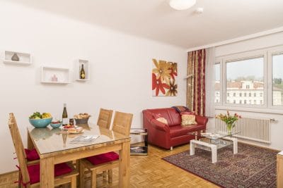 Apartment F21/17 Wohnzimmer mit roter Couch und Esstisch